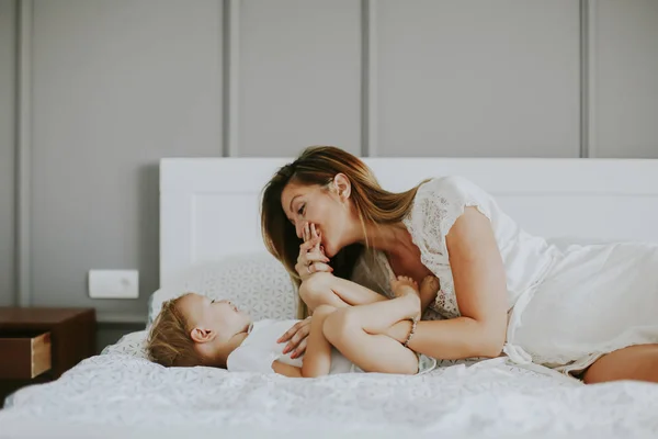 Mamma leker med liten pojke på sängen i rummet — Stockfoto