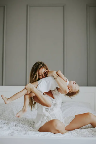 Yatağa küçük çocuk ile oynarken annesi — Stok fotoğraf