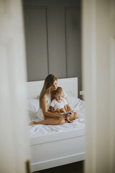 Mor och Lille son med tablett på säng — Stockfoto