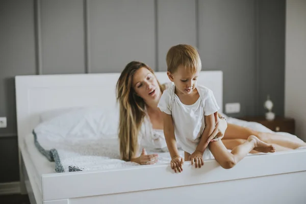 Mamma leker med liten pojke på sängen — Stockfoto