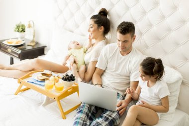 Yatağın içinde laptop ile genç aile