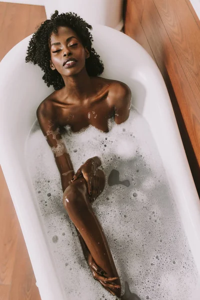 Genç afro Amerikalı genç kadın köpük banyosunda döşeme