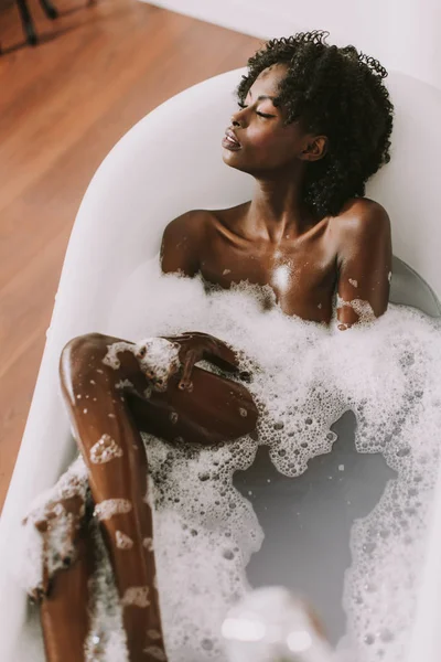 Joven afroamericana joven tendida en baño con espuma — Foto de Stock