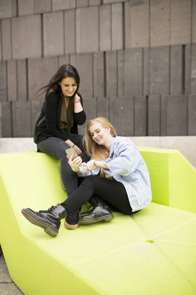 Young women sitting in the city and use a mobile phone — Stock Photo, Image