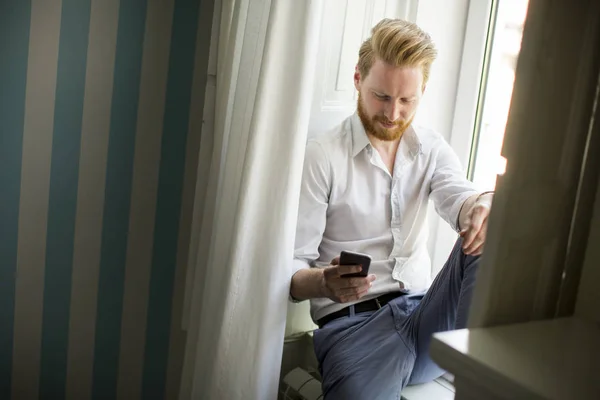 Человек с бородой и рыжими волосами с помощью смартфона — стоковое фото