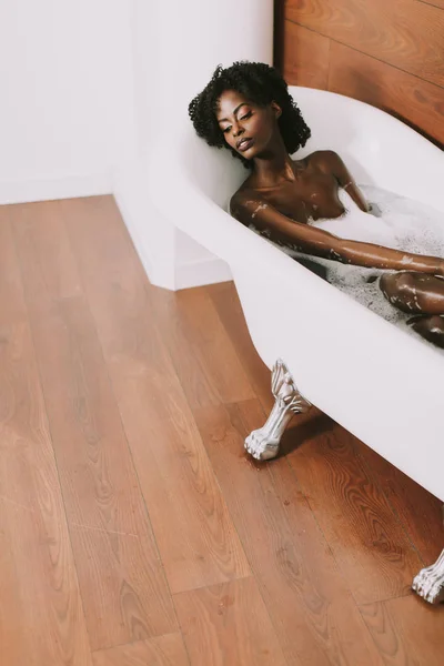 젊은 아프리카 미국 젊은 여자 거품 욕조에 누워 — 스톡 사진