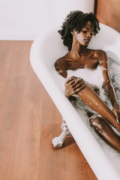 Joven afroamericana joven tendida en baño con espuma —  Fotos de Stock