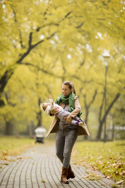 Madre joven con hija en el parque de otoño — Foto de Stock