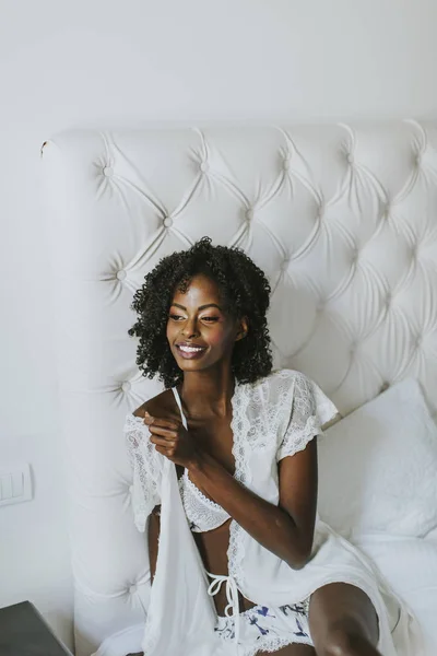 सफेद में अफ्रीकी अमेरिकी महिला बिस्तर पर पोज़िंग — स्टॉक फ़ोटो, इमेज