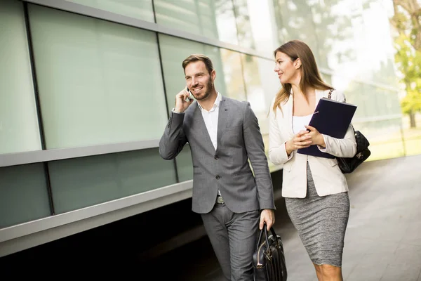 Jonge bedrijf paar lopend en pratend aan de telefoon — Stockfoto