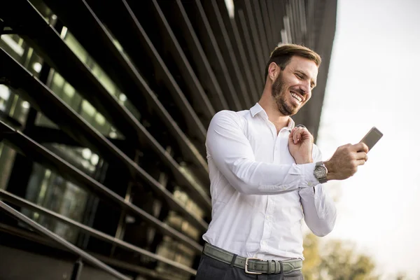 Glücklich lächelnder urbaner Geschäftsmann mit Smartphone — Stockfoto