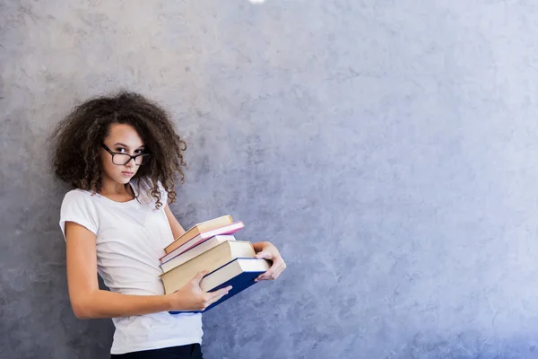 Tienermeisje staat door de muur en houdt van boeken — Stockfoto