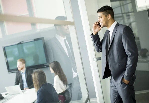 Jeune homme d'affaires africain utilisant le téléphone portable dans son bureau . — Photo