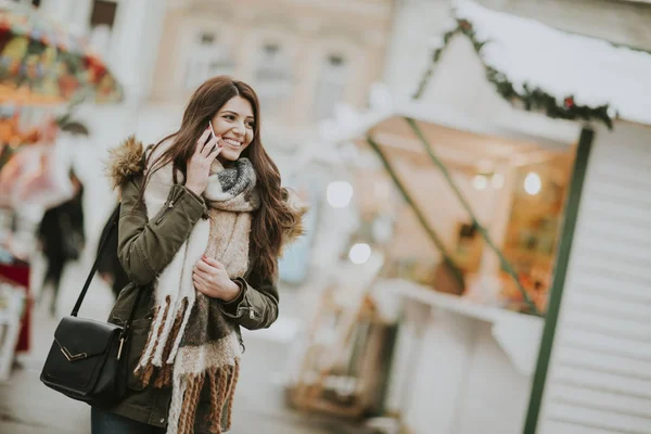 Giovane donna che utilizza il telefono nel parco nella fredda giornata invernale — Foto Stock