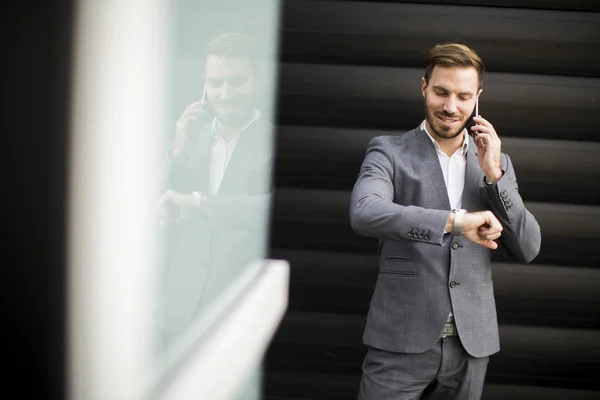 Empresario usando teléfono móvil y mirando el reloj — Foto de Stock