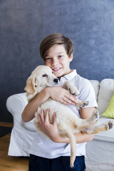 Симпатичний хлопчик-підліток з дитиною собакою-ретривером в кімнаті — стокове фото