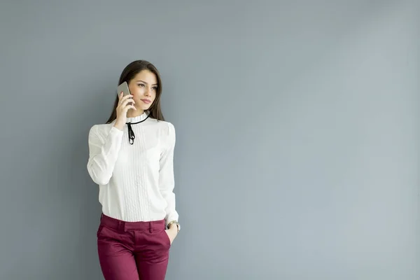 Elegante zakenvrouw met mobiele telefoon door de muur — Stockfoto