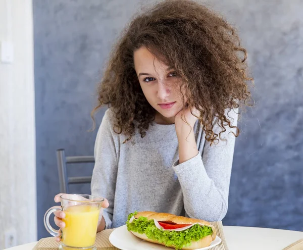 Pelo rizado adolescente chica teniendo desayuno en casa — Foto de Stock