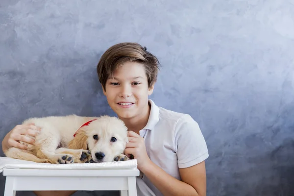 Cute teen boy with baby retriever dog in room — Stock Photo, Image