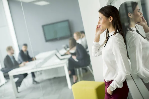 Moderne zakenvrouw met behulp van een mobiele telefoon terwijl mensen uit het bedrijfsleven — Stockfoto