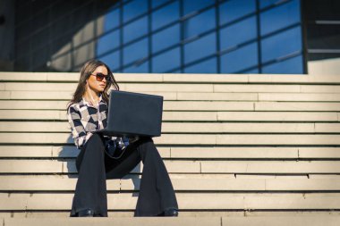 Çekici kadın merdivenlerde açık dizüstü bilgisayar kullanarak