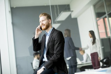 Cep telefonu kullaranarak Kızıl saçlı işadamı 