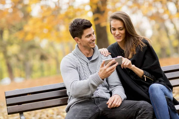 Giovane coppia felicemente guardando qualcosa su uno smartphone — Foto Stock