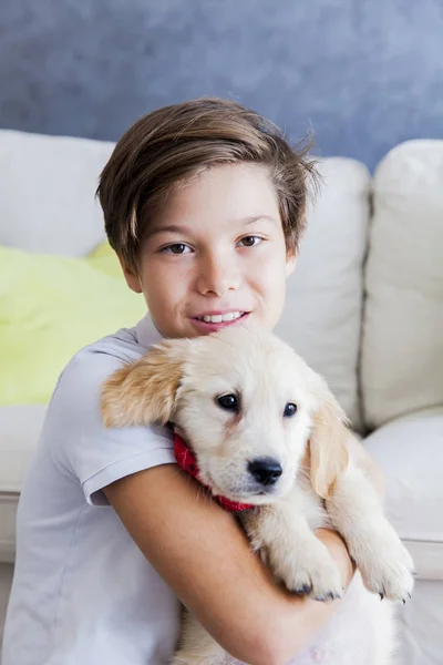 Cute teen boy with baby retriever dog in room — Stock Photo, Image