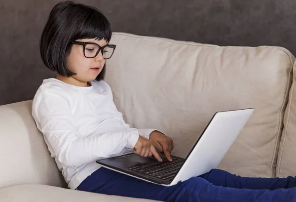 Маленька дівчинка в окулярах використовує свій ноутбук — стокове фото
