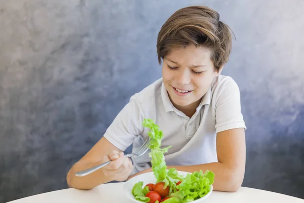 Adolescente chico comer ensalada infeliz — Foto de Stock