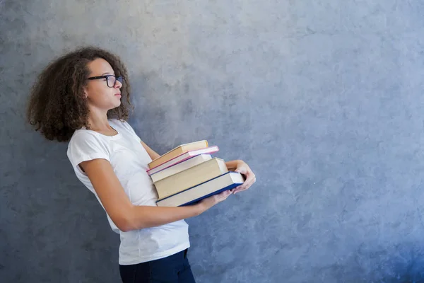 Tizenéves lány szemüveges és tart több könyvet — Stock Fotó