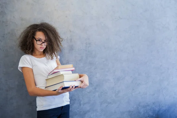 Adolescente con gafas y sostiene varios libros — Foto de Stock