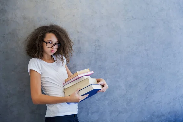 Adolescente avec des lunettes et détient plusieurs livres — Photo