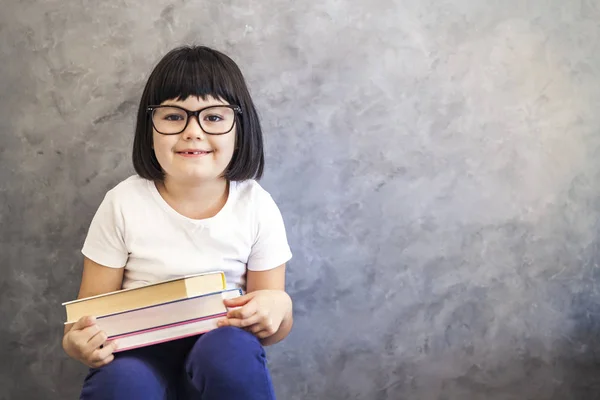 Mignon cheveux noirs petite fille avec des lunettes tenant des livres — Photo