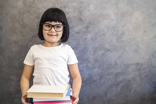 Mignon cheveux noirs petite fille avec des lunettes tenant des livres — Photo