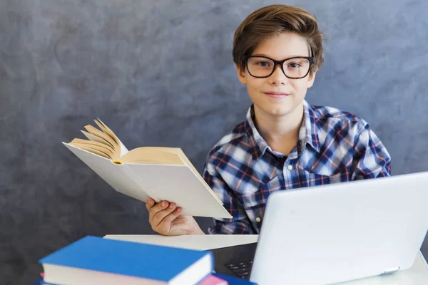 Olvasó a könyvet, és használ laptop otthon tini fiú — Stock Fotó