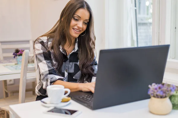 Vrouw die op haar laptop in een café werkt — Stockfoto