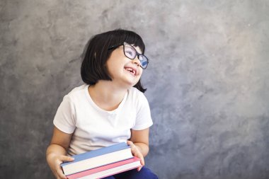 Sevimli siyah saçlı gözlüklü kitap tutan küçük kız 