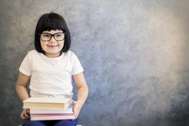 Sevimli siyah saçlı gözlüklü kitap tutan küçük kız