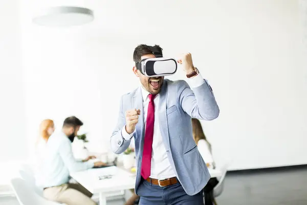 Empresário com fones de ouvido de realidade virtual no escritório — Fotografia de Stock
