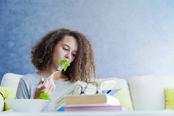 Krullend haar tiener meisje boek lezen en eten Salade — Stockfoto