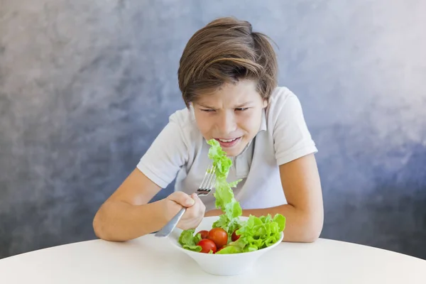 Adolescente chico comer ensalada infeliz — Foto de Stock