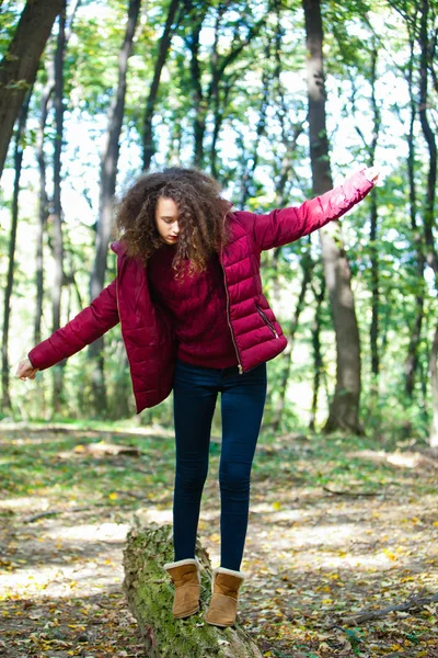 Teenagermädchen läuft in einem Herbstwald einen umgestürzten Stamm hinunter — Stockfoto