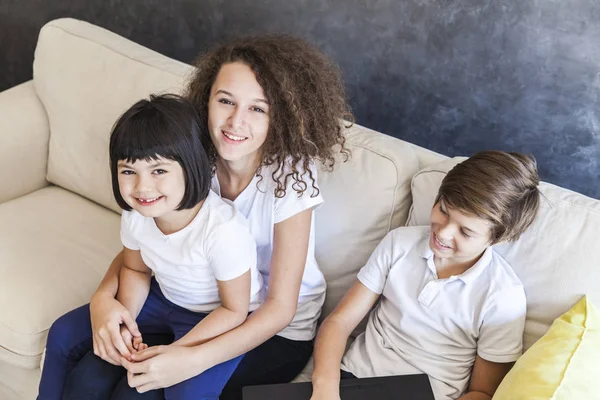 Little girl, teen boy and curly hair girl with laptop on sofa — Stock Photo, Image