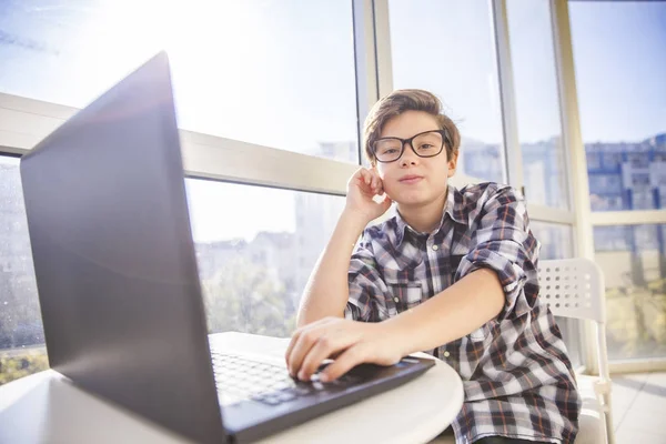 Adolescente menino usando laptop por janela — Fotografia de Stock