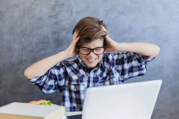 Arga tonårspojke som arbetar på bärbar dator hemma — Stockfoto