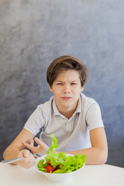 Lindo adolescente chico comer ensalada —  Fotos de Stock