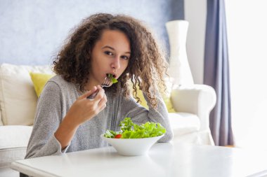 Kıvırcık saçlı genç kız salata yemek