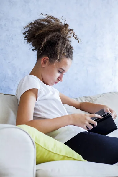 Göndör haj lány segítségével digitális tábla kanapéval — Stock Fotó
