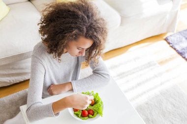 Kıvırcık saçlı genç kız salata yemek, üstten görünüm